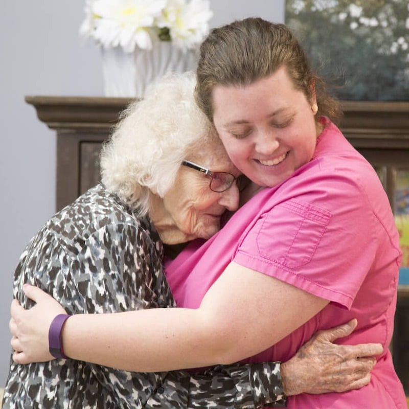 caregiver and senior hugging