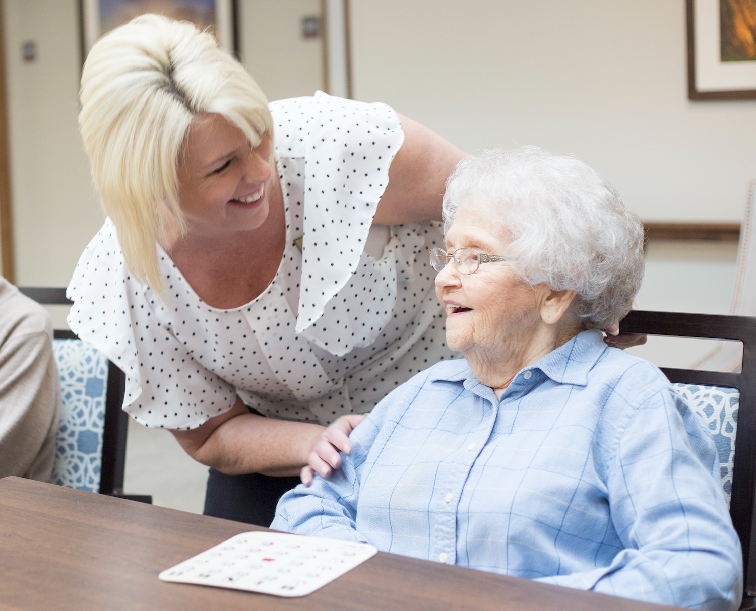 A senior woman playing a board game with a staff member