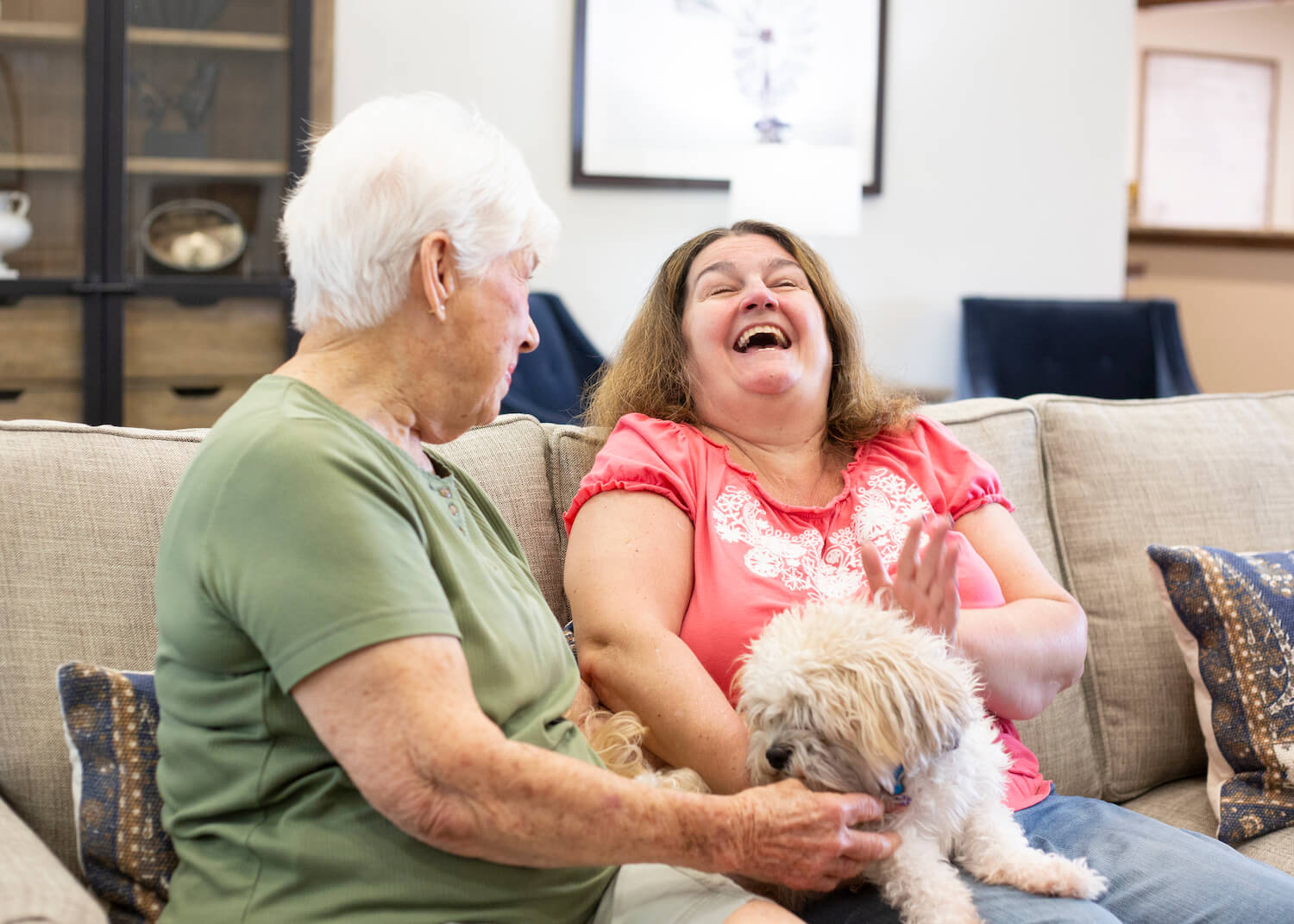 women sitting on a couch with a dog 