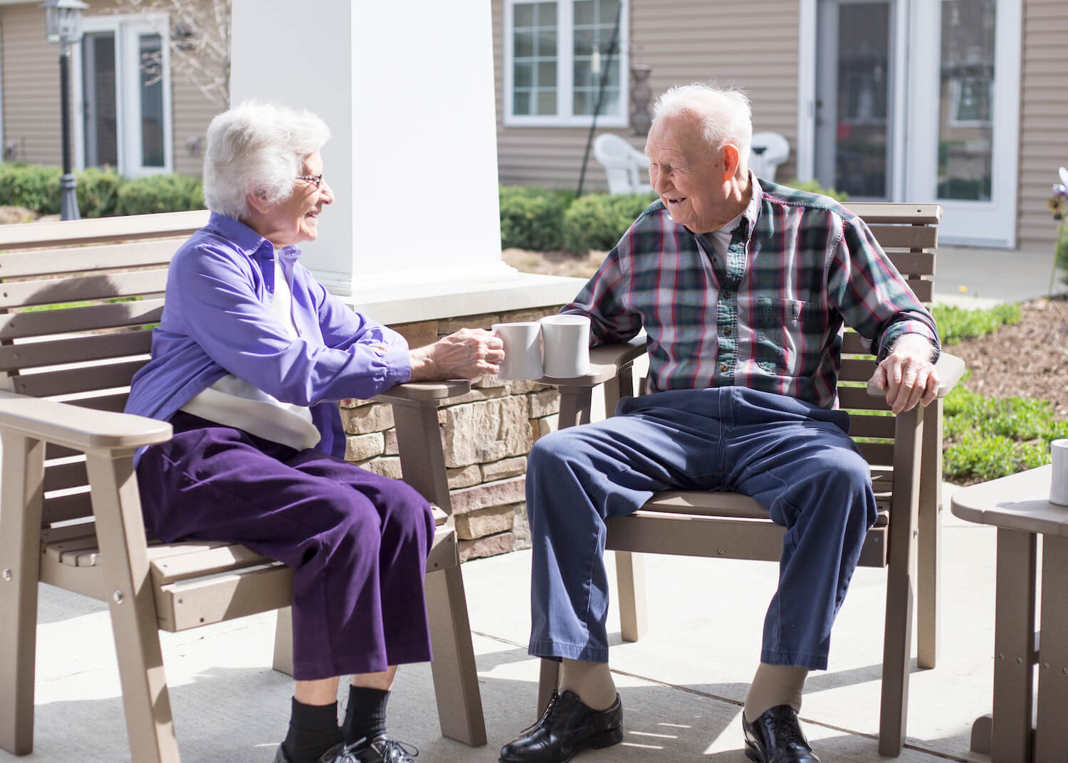 Seniors drinking coffee outside on patio chairs