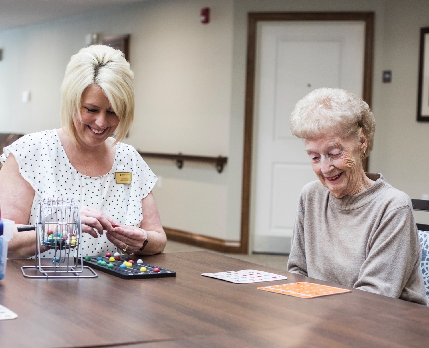A staff member and senior resident playing bingo