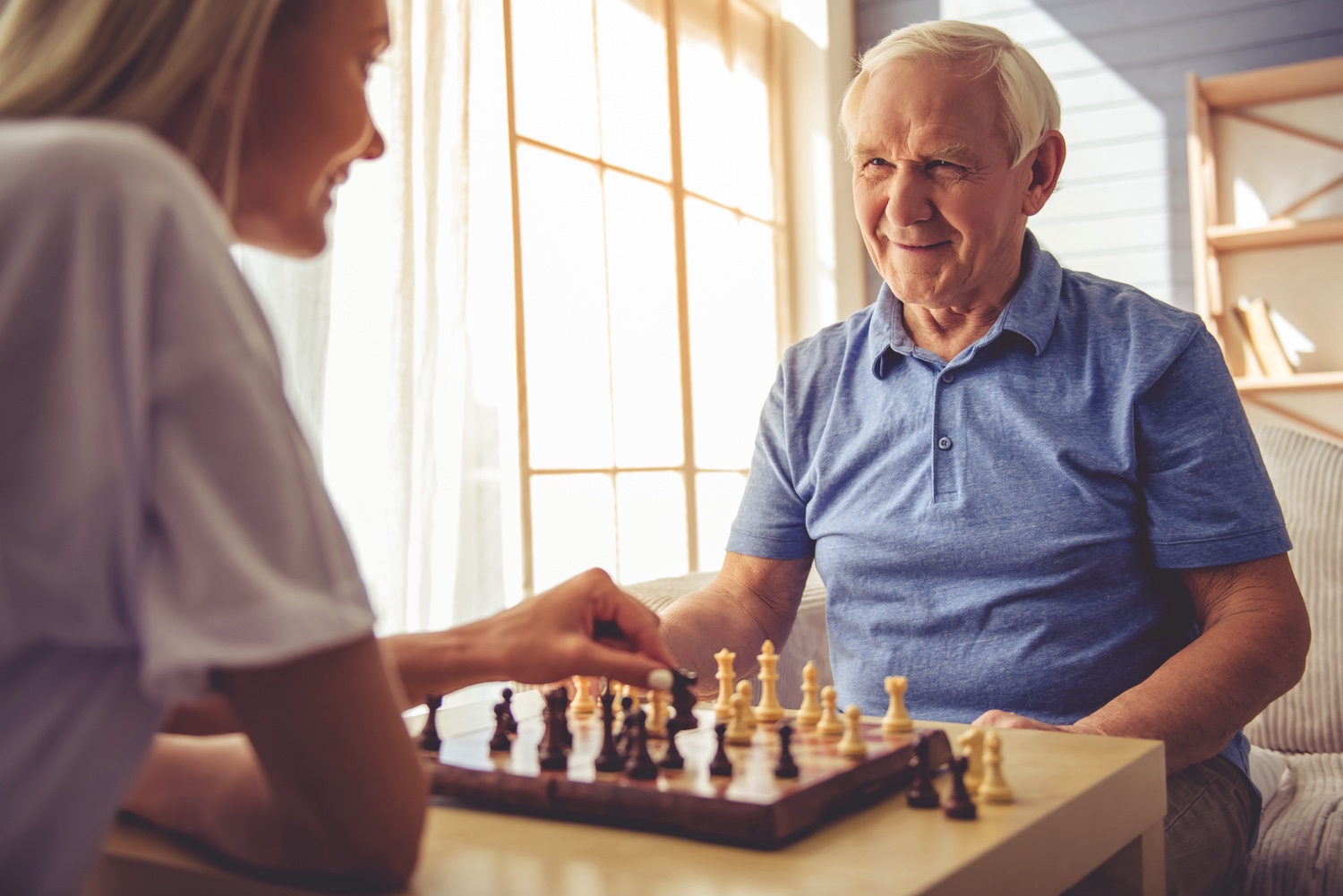 Staff member playing chess with senior man