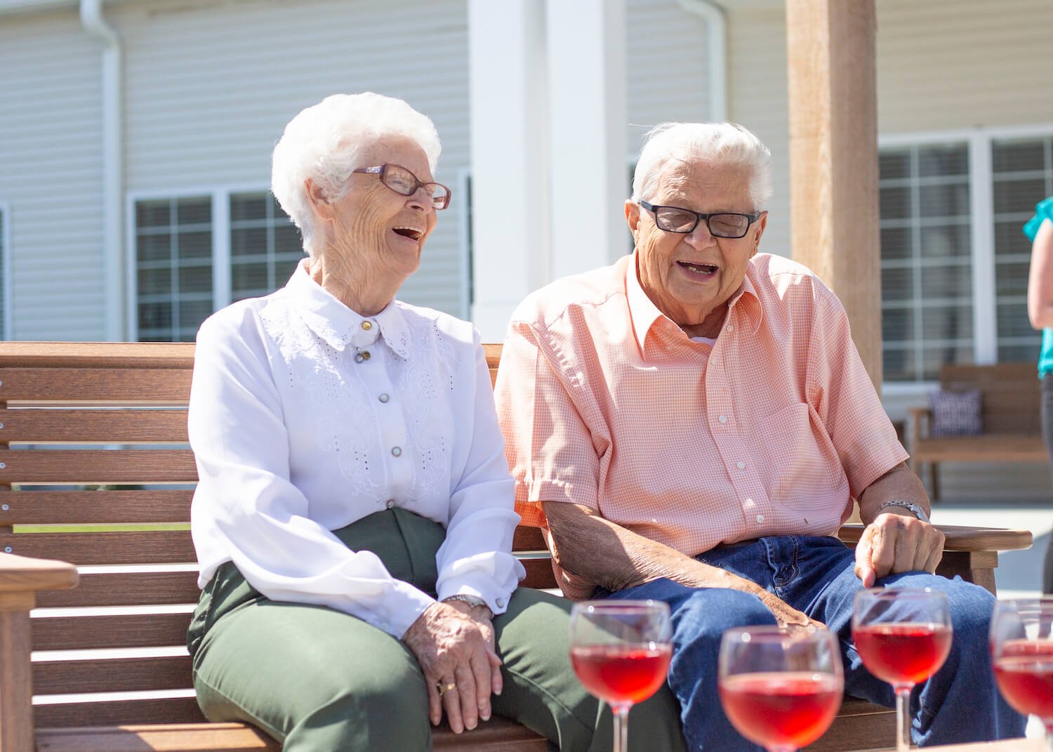 Two senior residents laughing on a bench outside