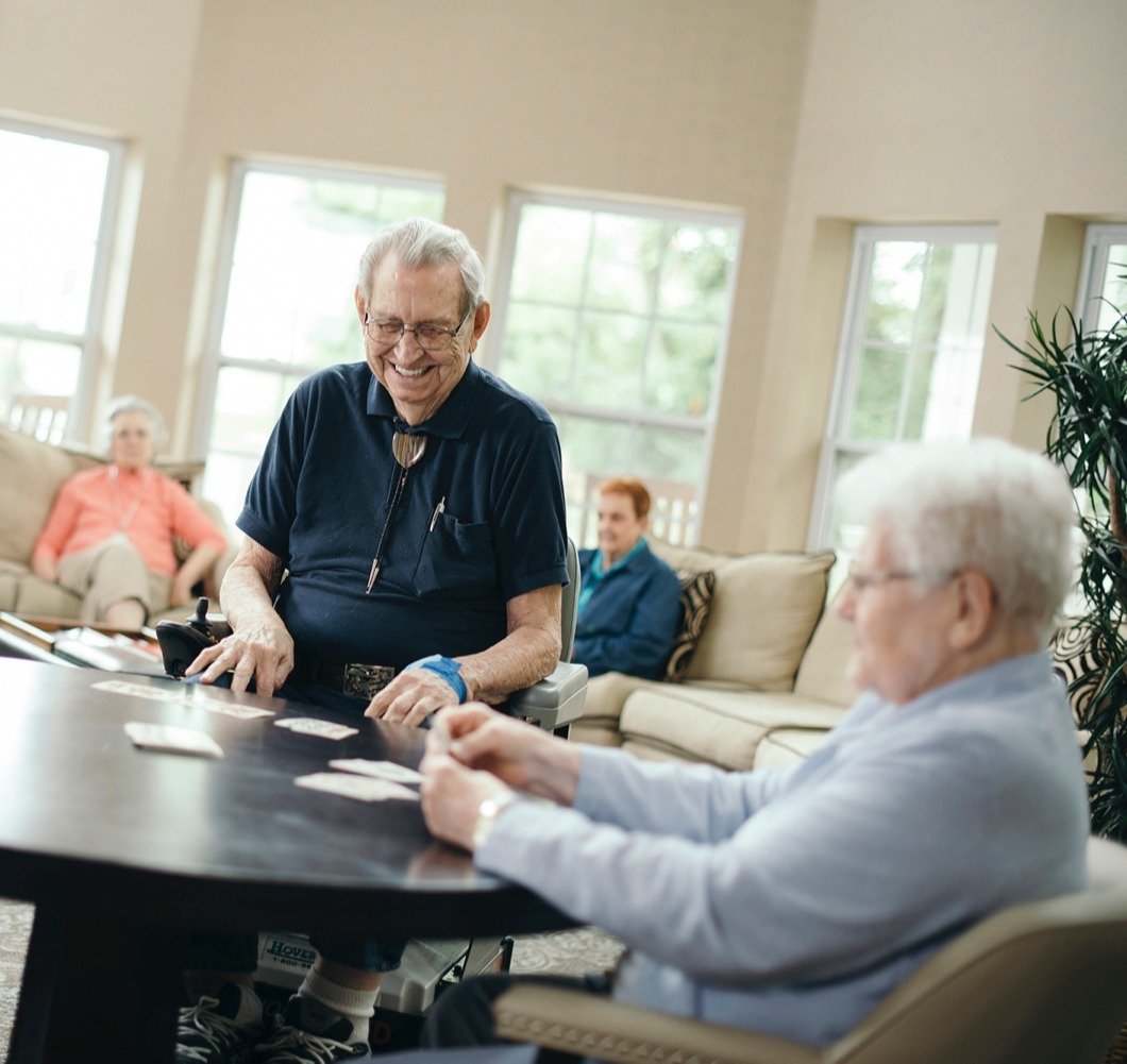 A group of seniors playing cards as friends look on