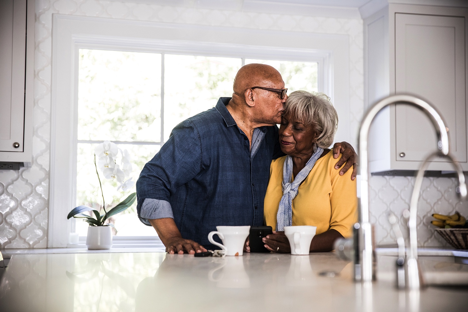 Senior couple sharing forehead kisses over coffee