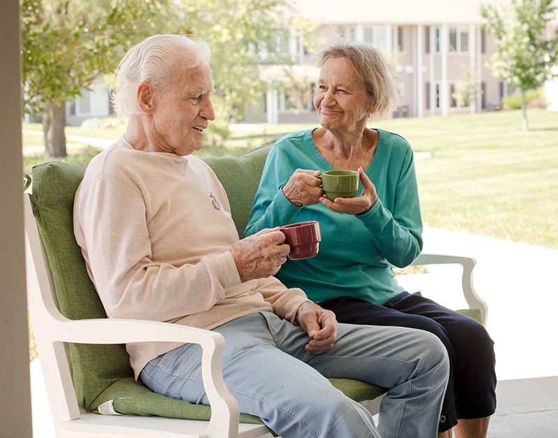 Seniors drinking coffee on an outdoor bench