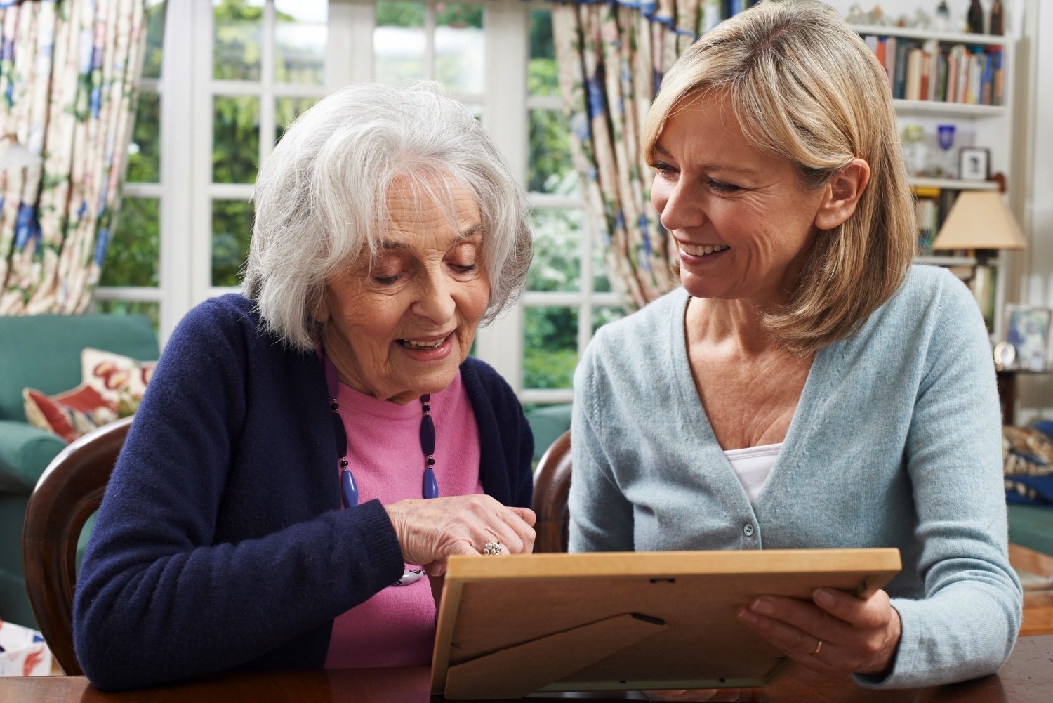 Senior resident views a photo frame with a caregiver