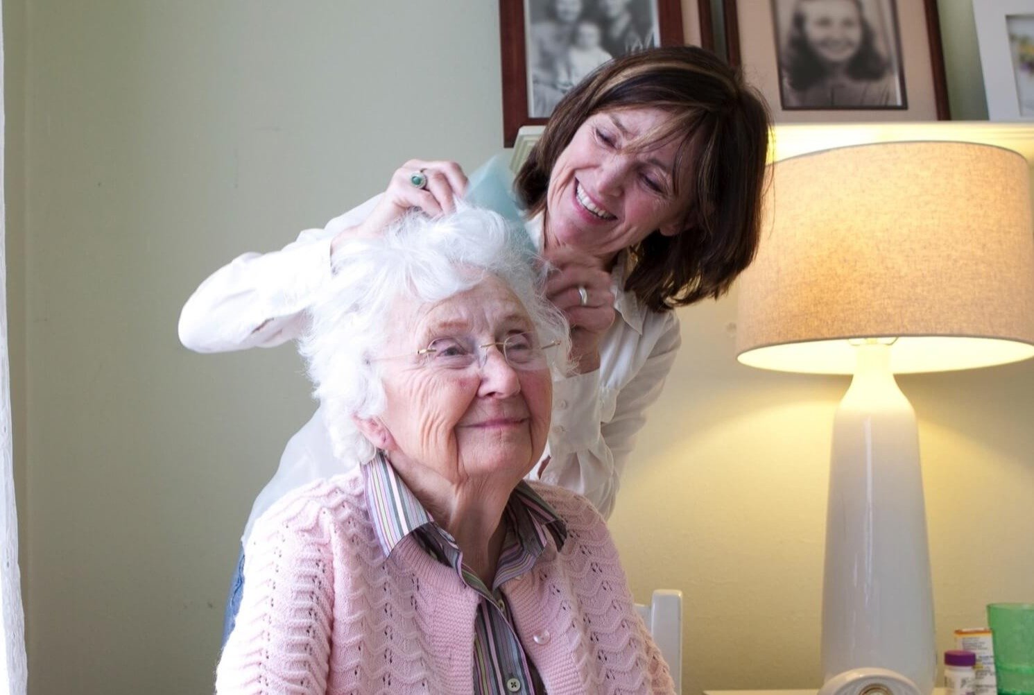 A staff member helping a senior resident style her hair