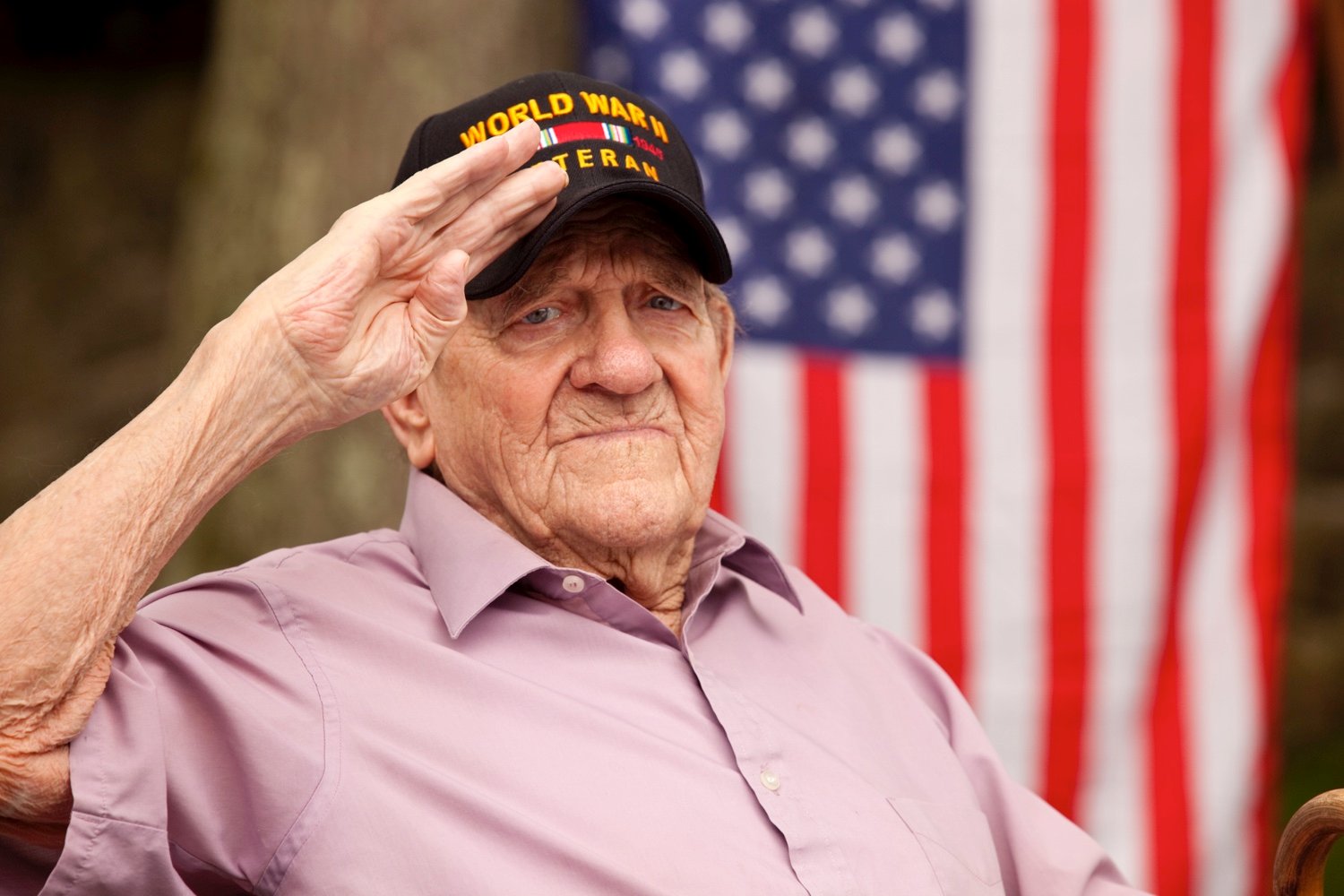 Senior veteran saluting with an American flag in the background