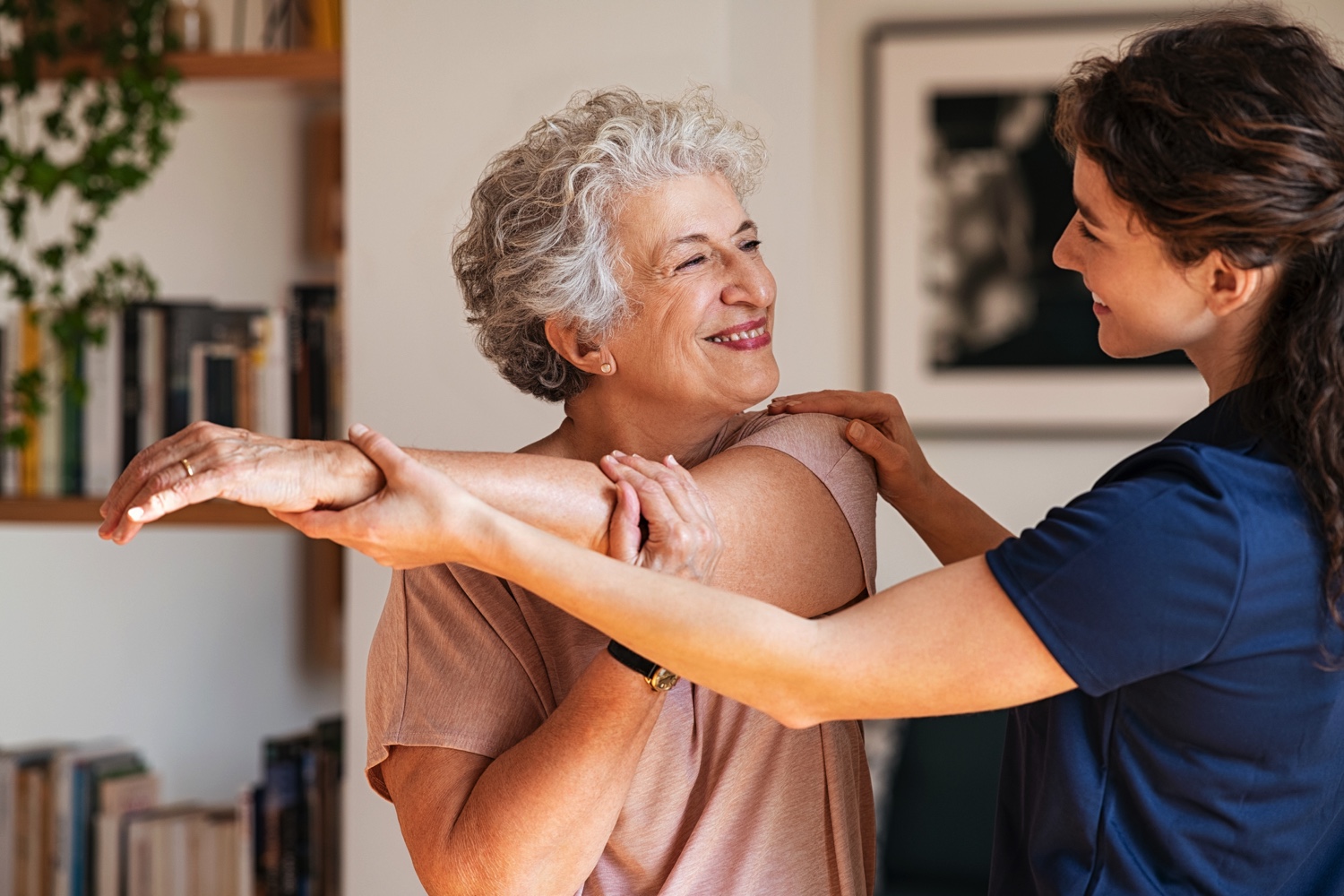 Senior woman with trainer exercising at home-1296176738