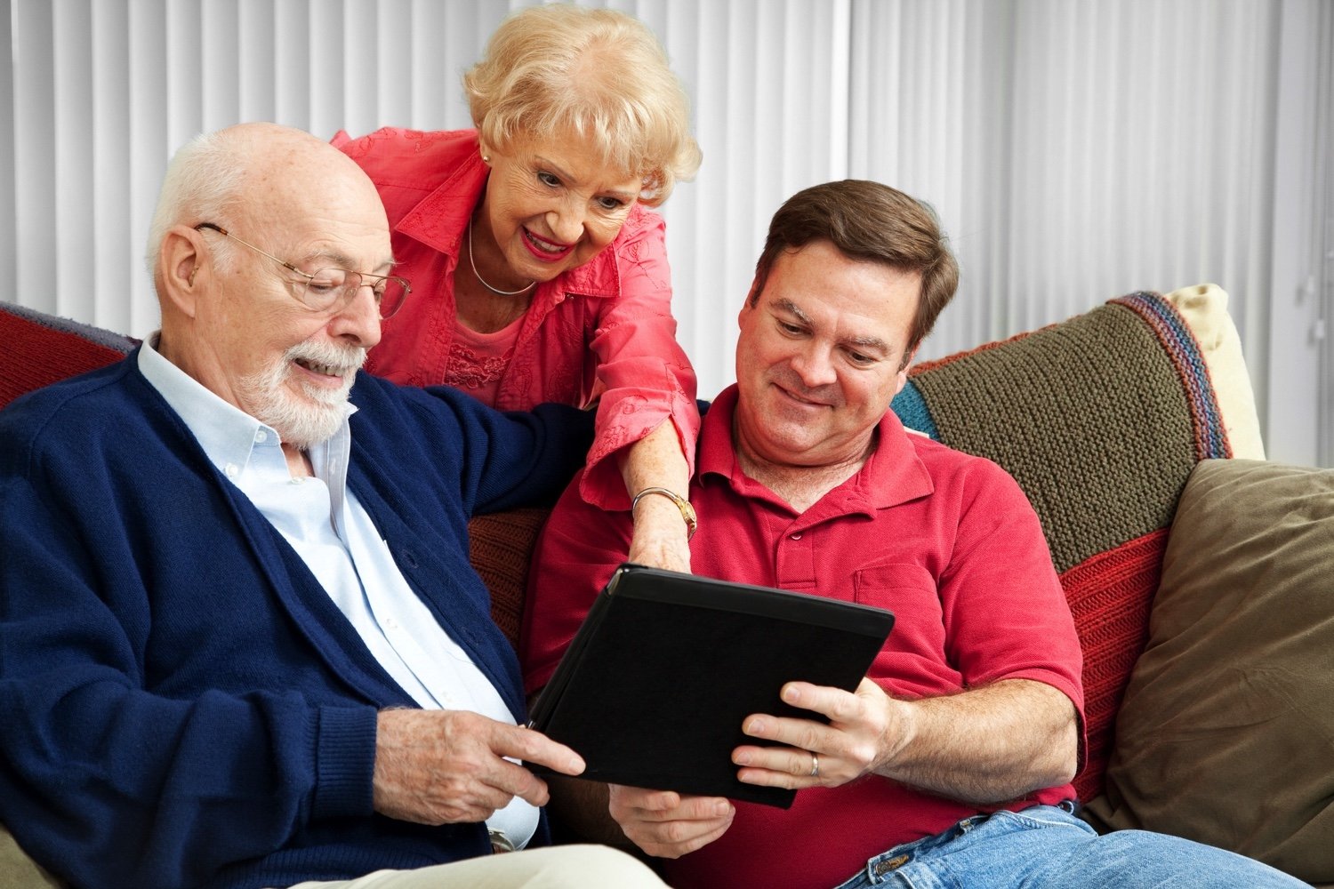 Staff member and two seniors reading a digital tablet together