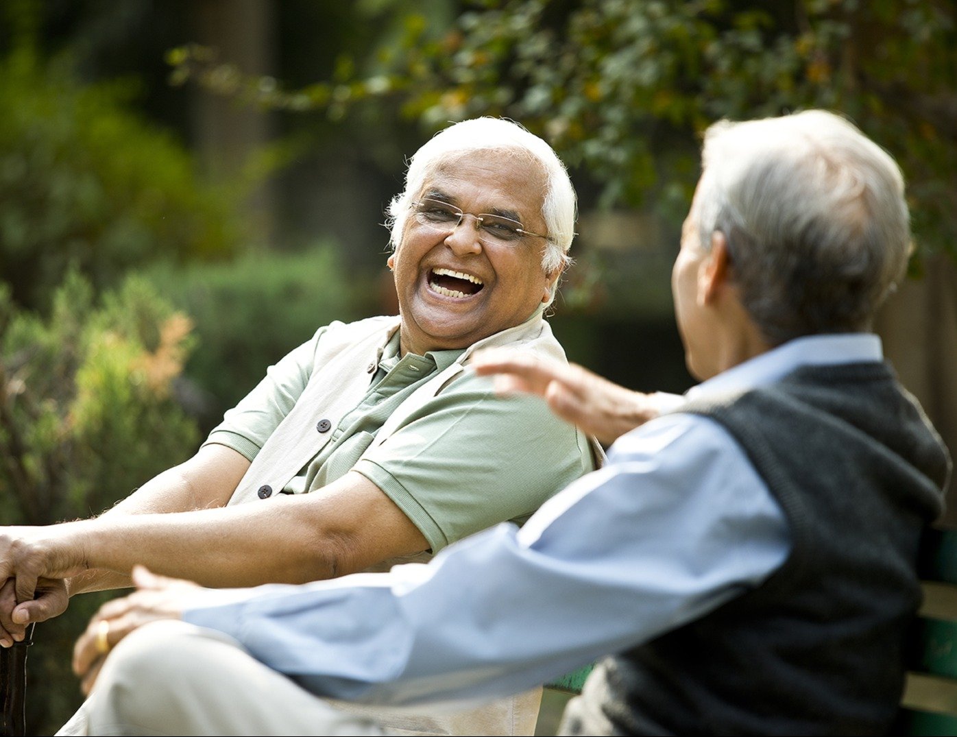 Two senior men laughing on a park bench