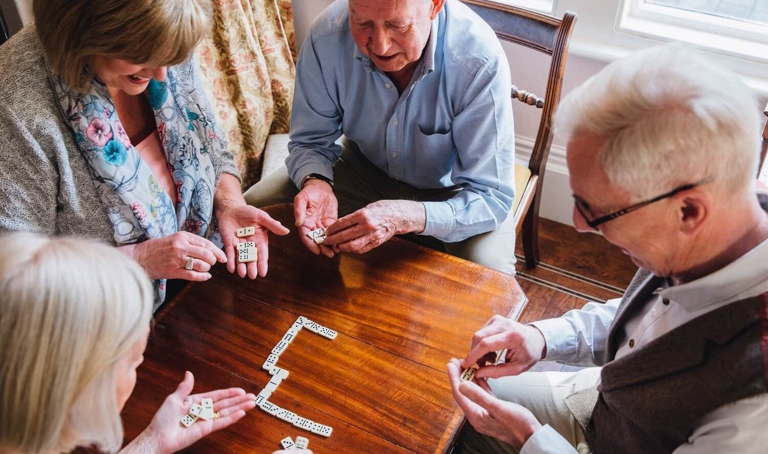 A group of four seniors playing dominos