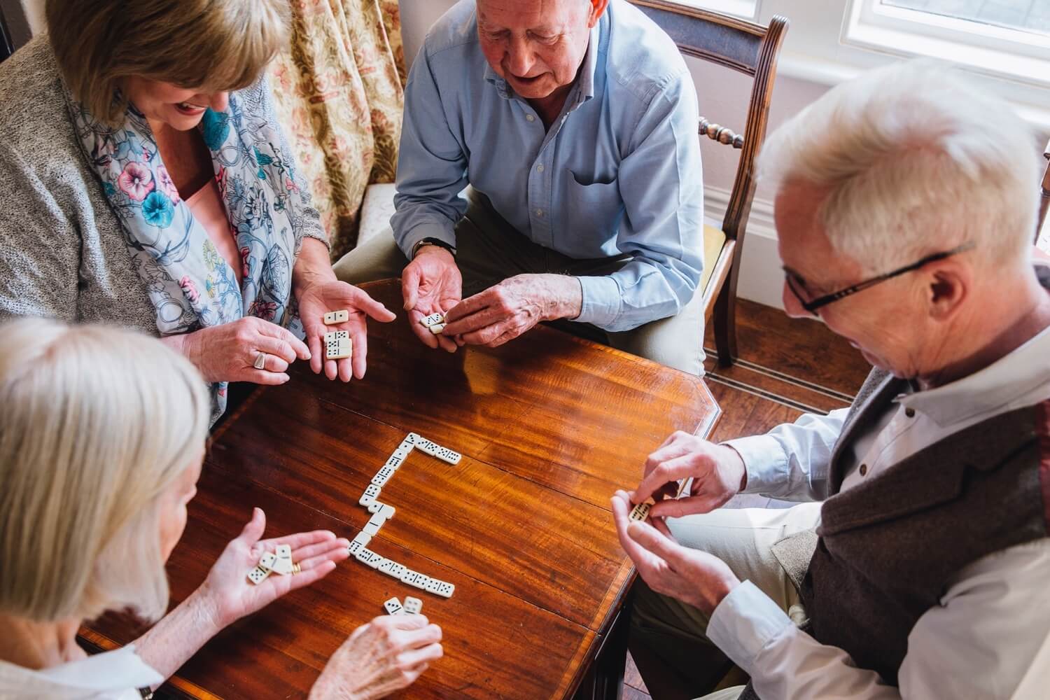 A group of four seniors playing dominos
