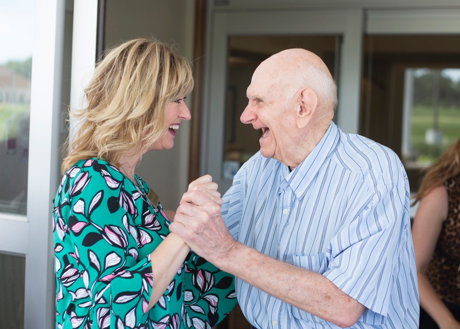 A female staff member dancing and laughing with a senior male resident
