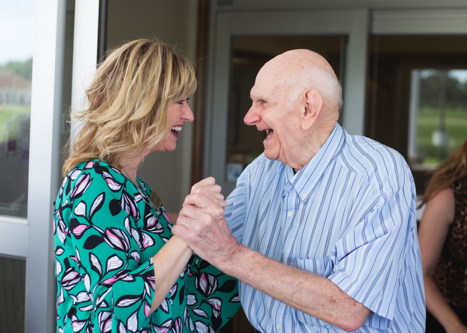 A female staff member dancing and laughing with a senior male resident