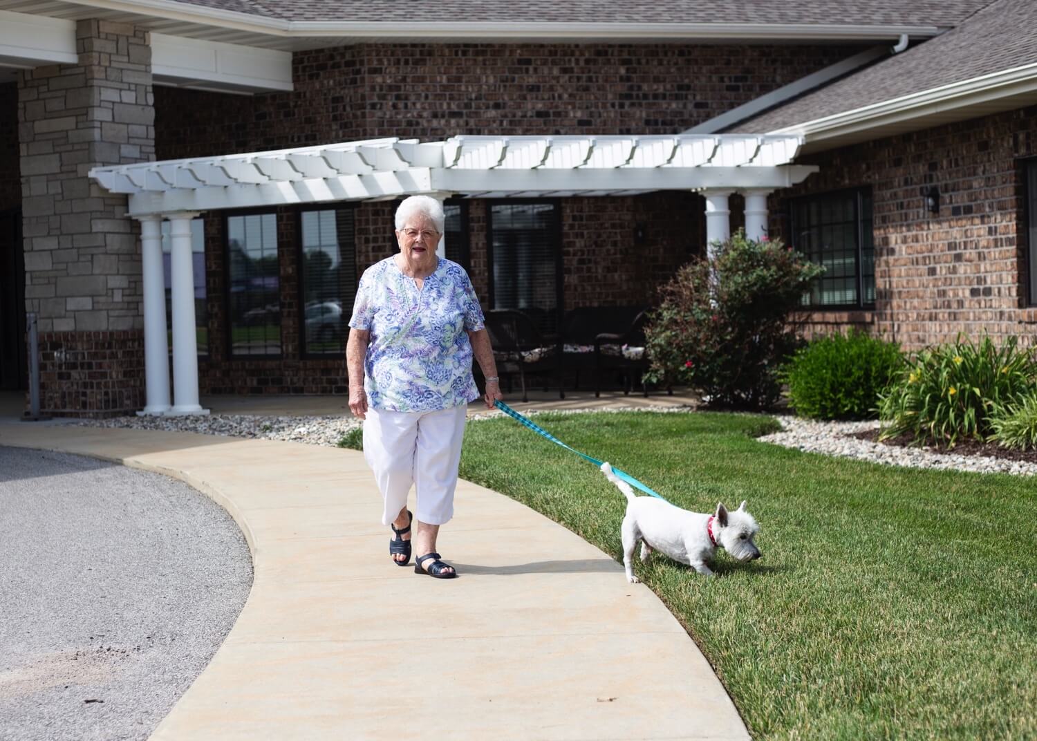 A woman walking her dog along the sidewalk