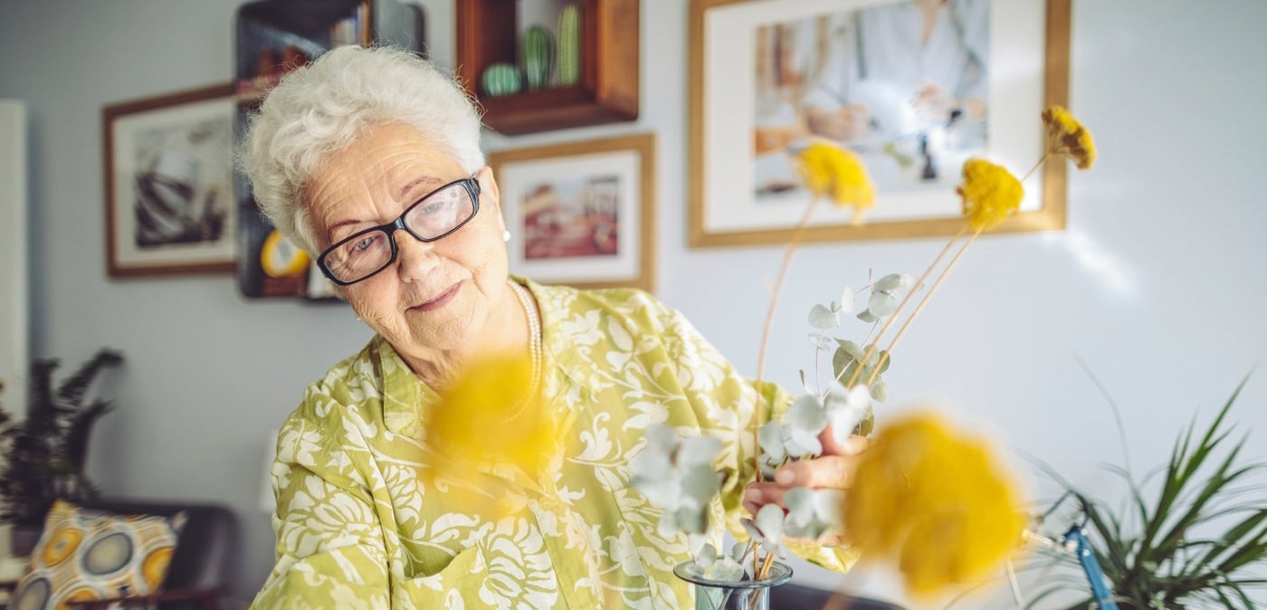 A senior woman arranging yellow flowers