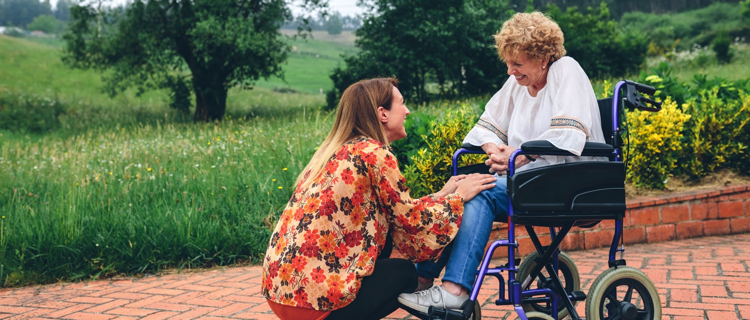 Young woman talking to elderly woman in a wheelchair