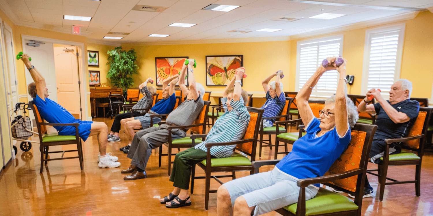 Assisted living residents participating in a group exercise session, lifting weights together to promote strength and wellness within their community.