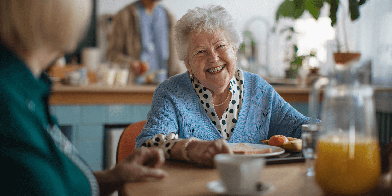 A woman in a senior living community happily enjoying a healthy lunch.