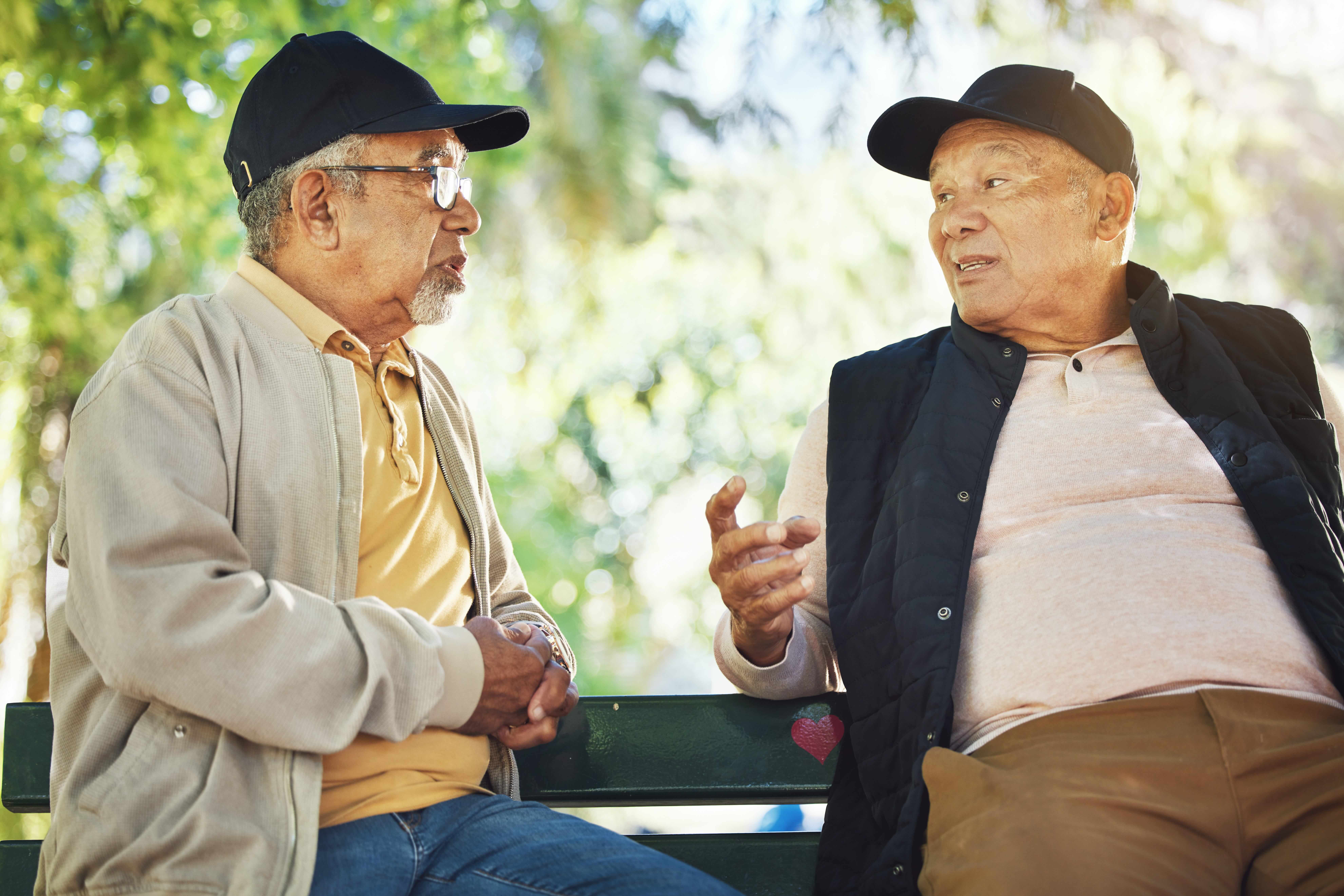 Two older adult men having a conversation outdoors at a senior living community
