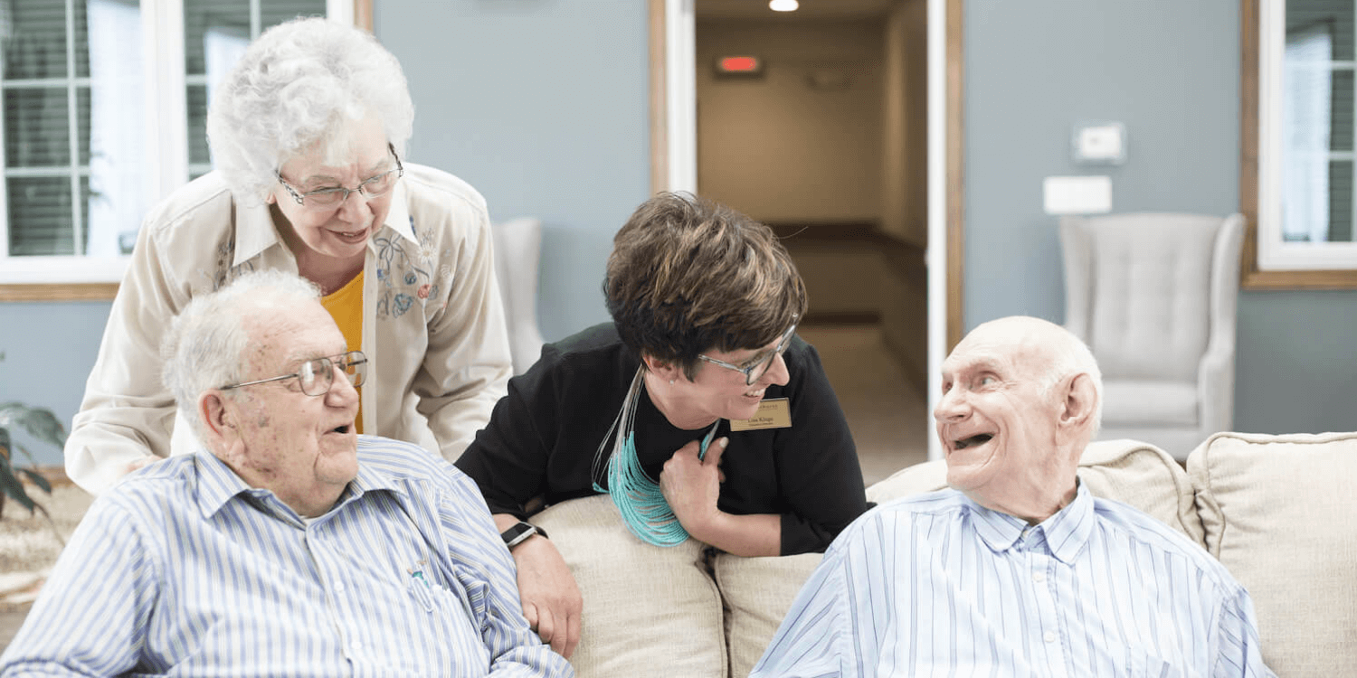 A Cedarhurst independent living team member chats with three residents on a couch