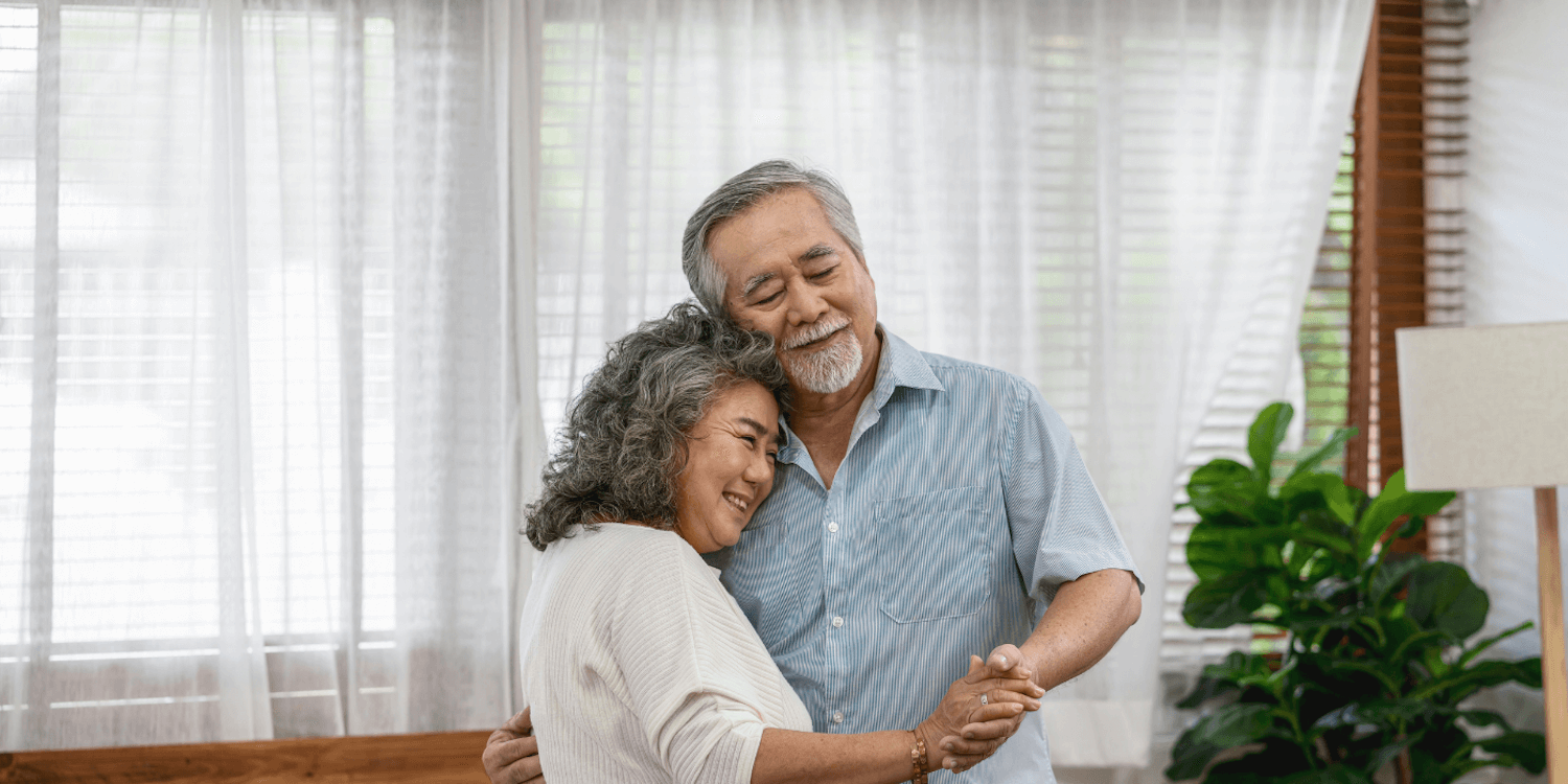 A resident couple standing together while hugging and holding hands 