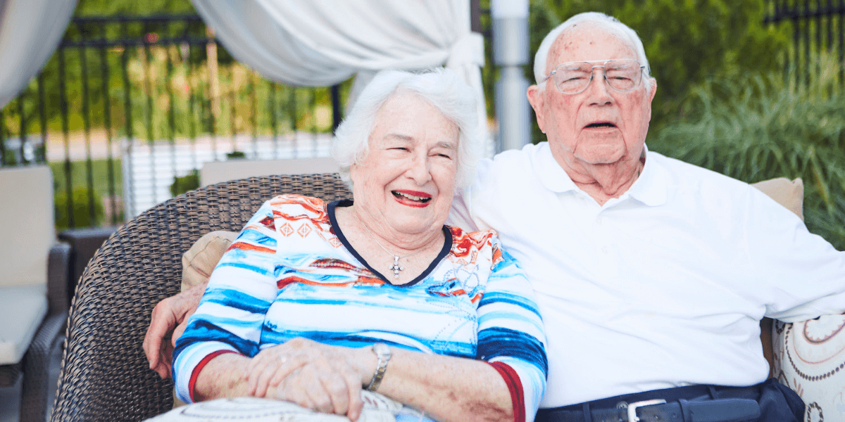 Two senior residents sitting outside on a patio together