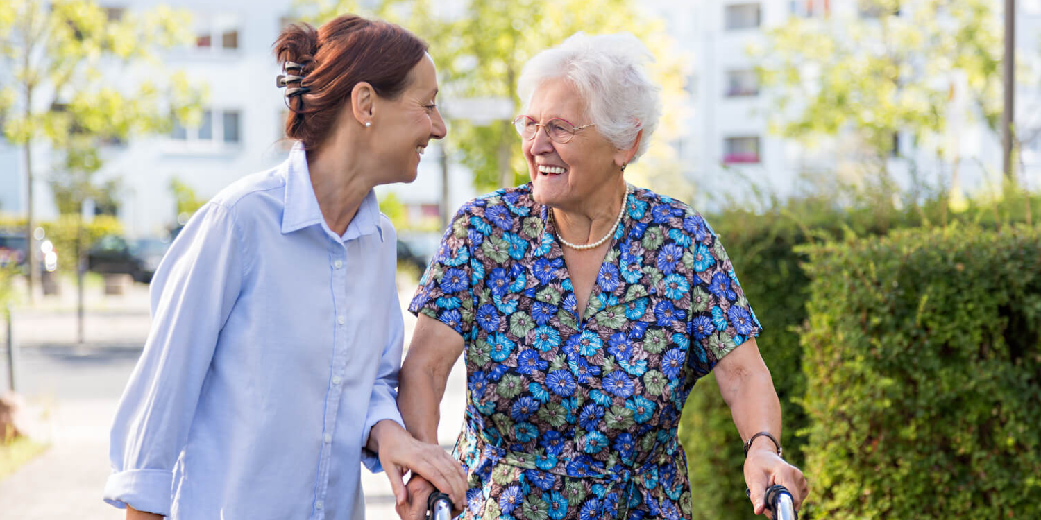 Woman walking outside with a senior resident in a dementia care community 