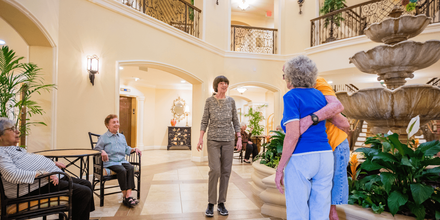 Senior residents socializing in a community atrium next to a fountain.