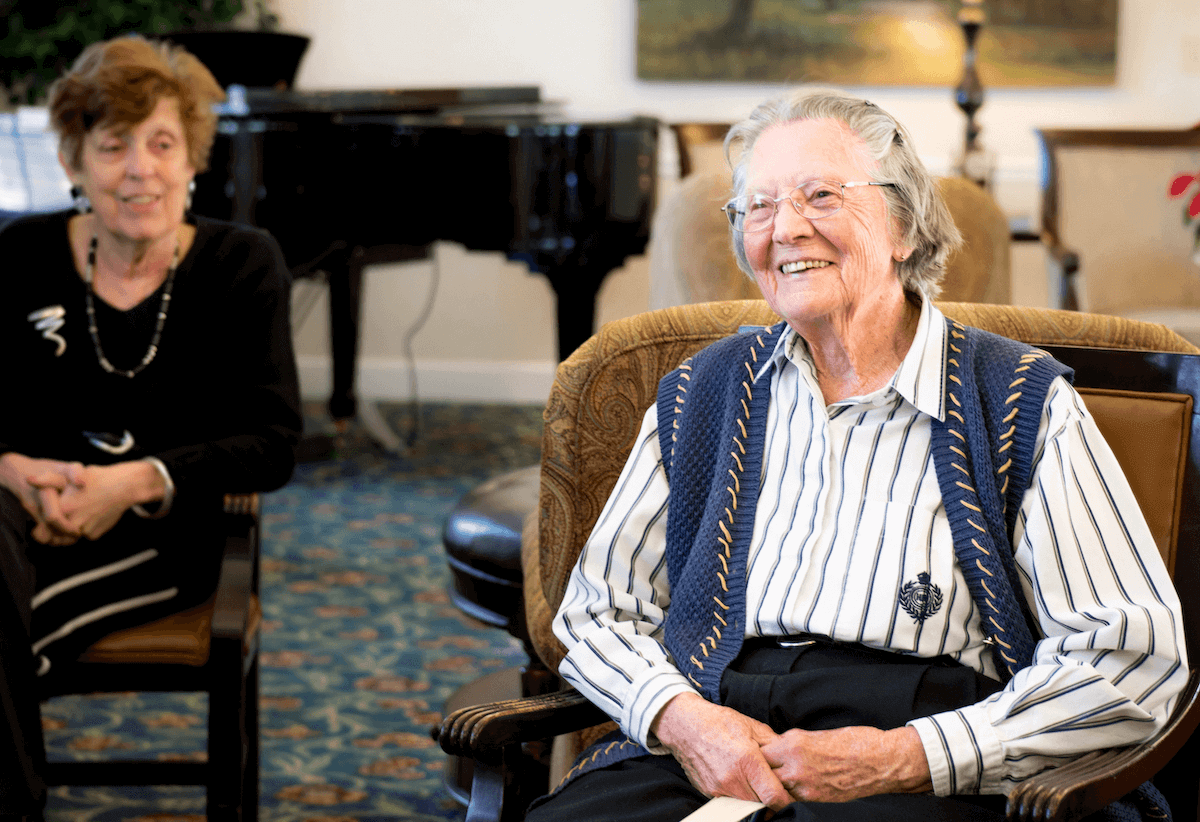 Smiling senior woman sitting in lounge at senior living community