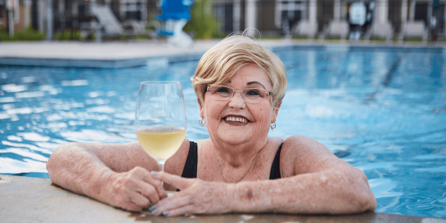 woman resident smiling and enjoying a glass of wine in the pool