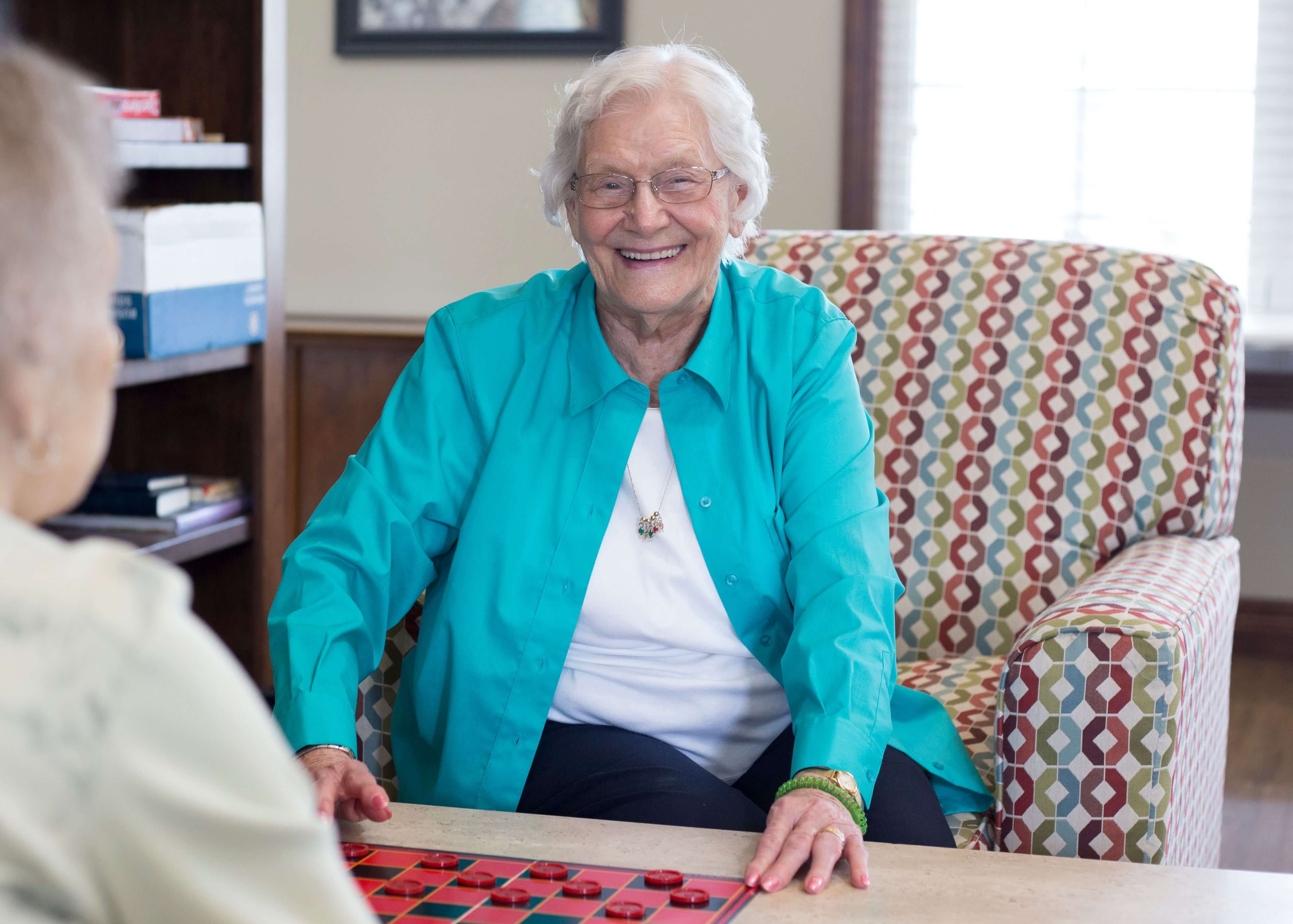 Two resident women smiling and playing checkers