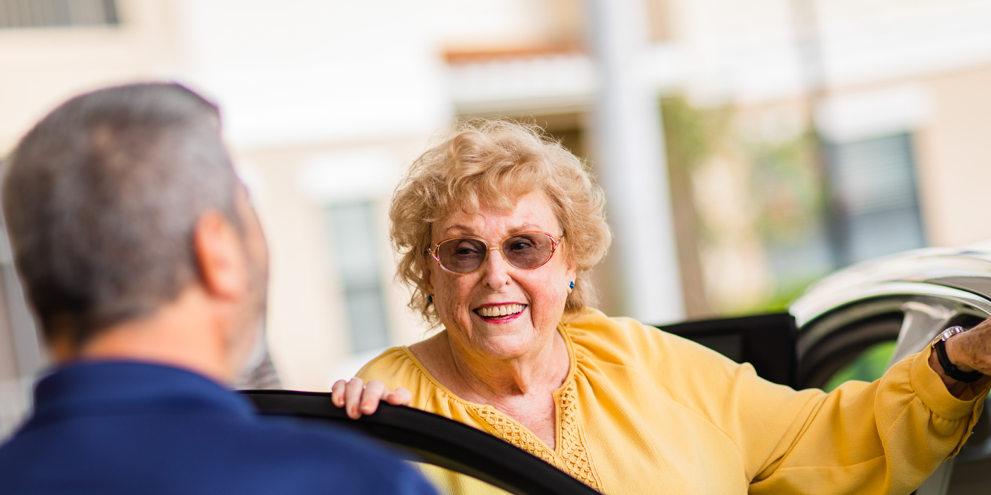 resident being welcomed by caregiver while getting out of her car