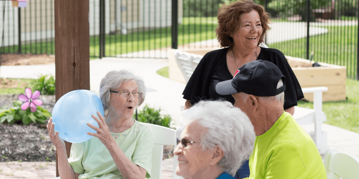 An outdoor senior socialization game being played by four people on a patio with a balloon