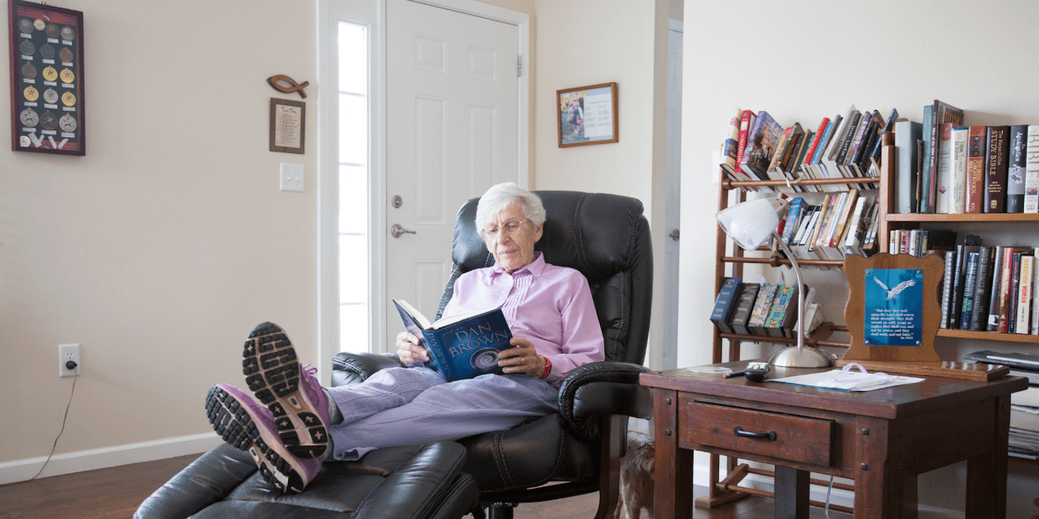 A Cedarhurst independent living resident reading and relaxing in a reclining chair