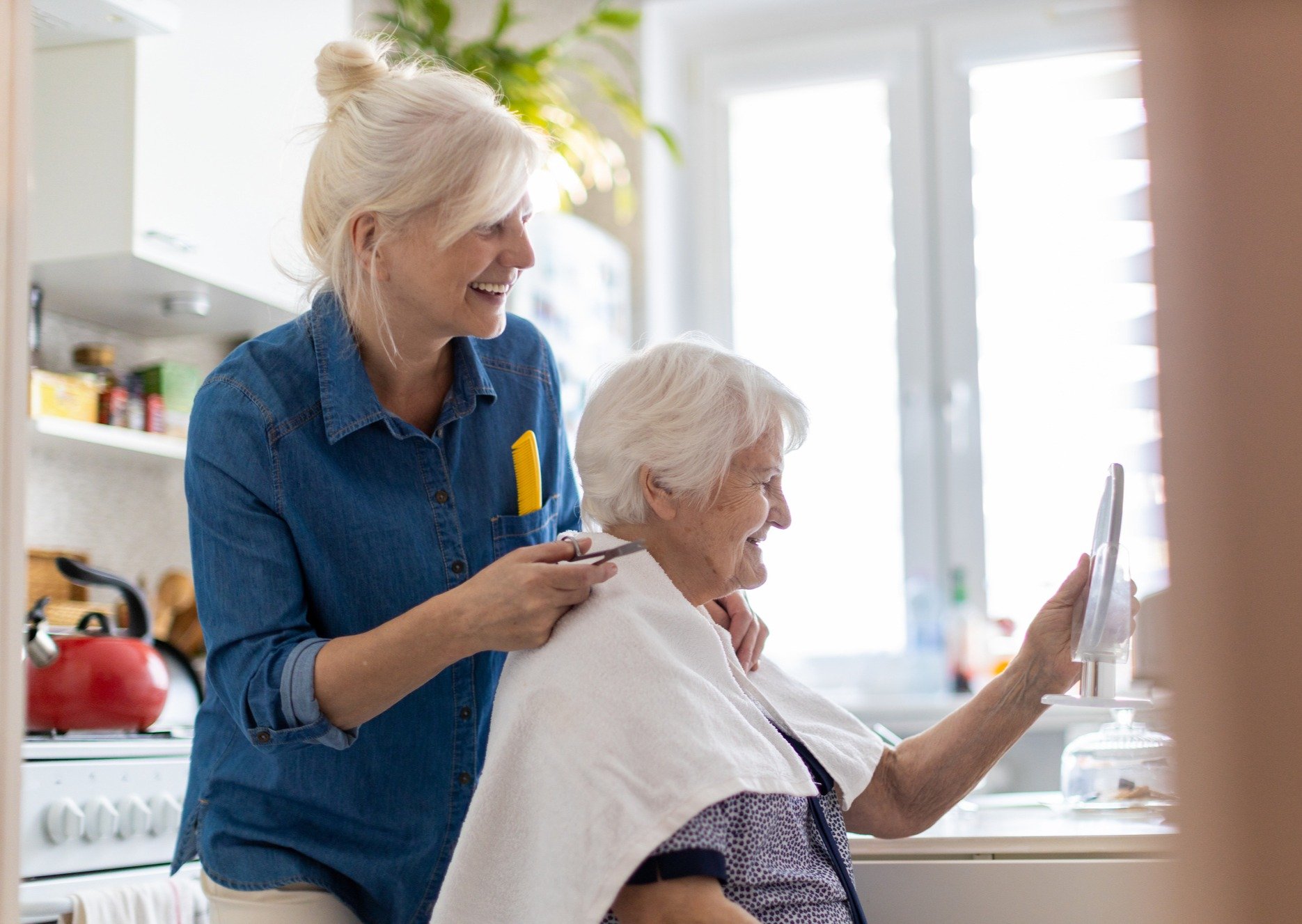 Carer cutting hair for senior