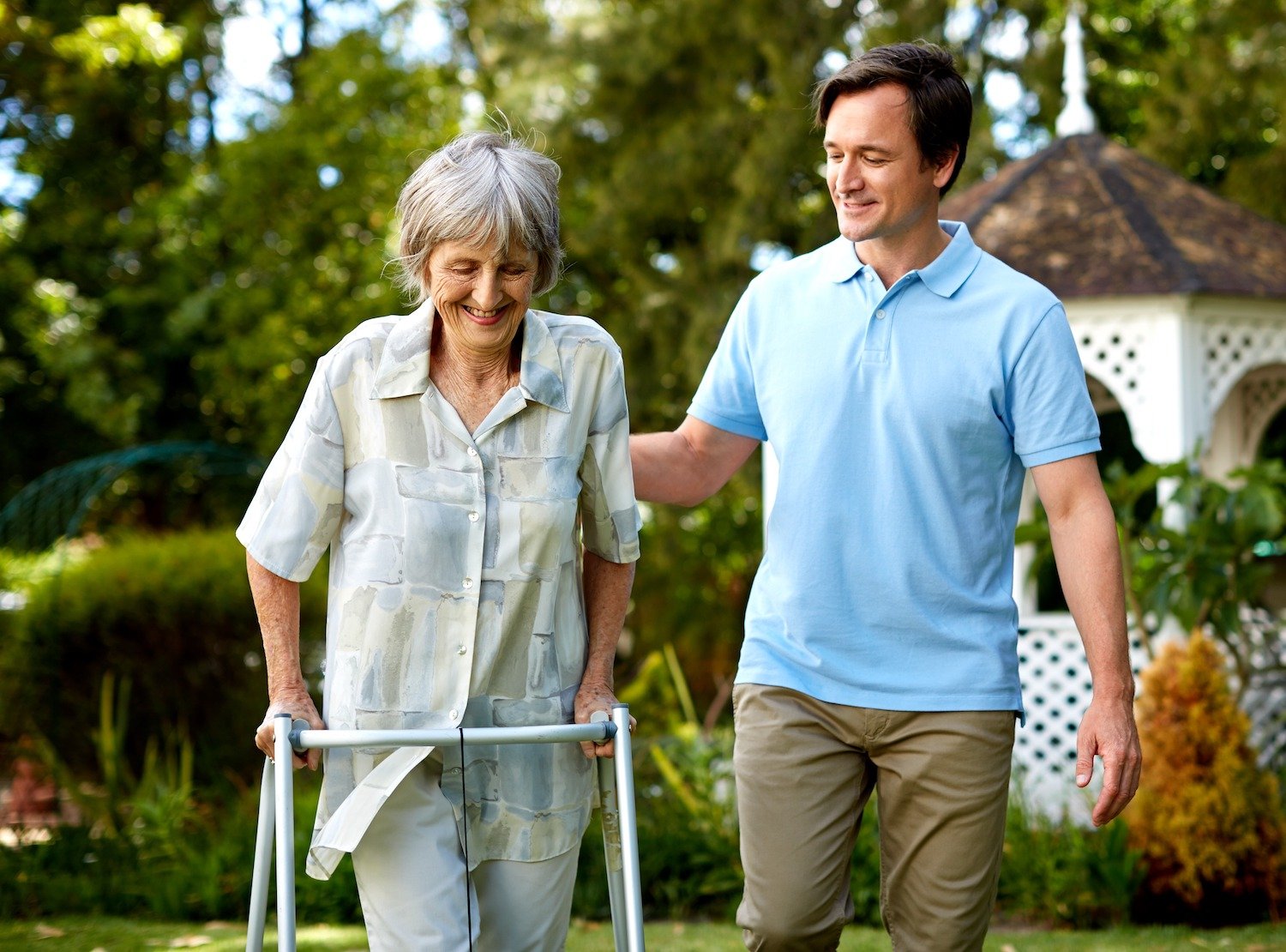 Staff member helping a woman with a walker in the garden