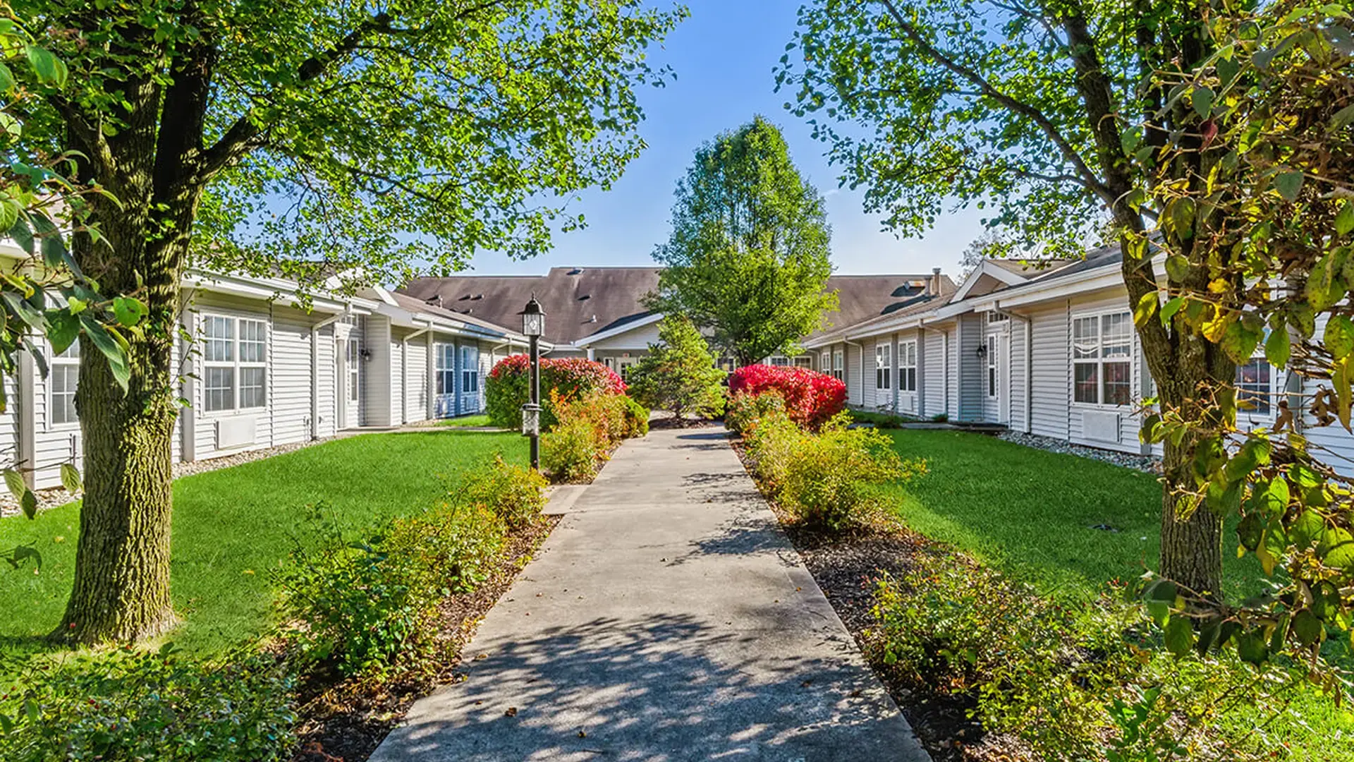An inviting outdoor area at Cedar Creek of Fort Wayne, showing lush green spaces and paved paths
