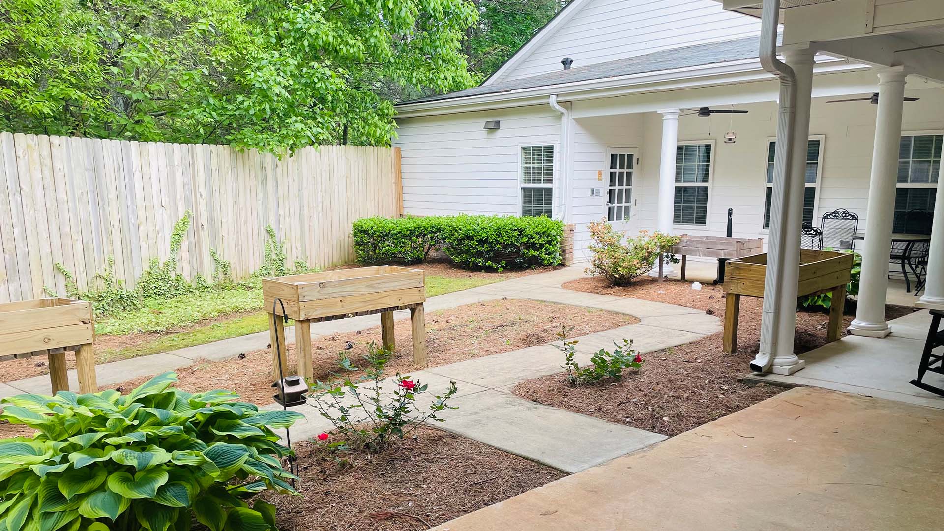 Outdoor green space at Cedarhurst of Oakwood with paved walking paths, covered seating, and raised garden beds