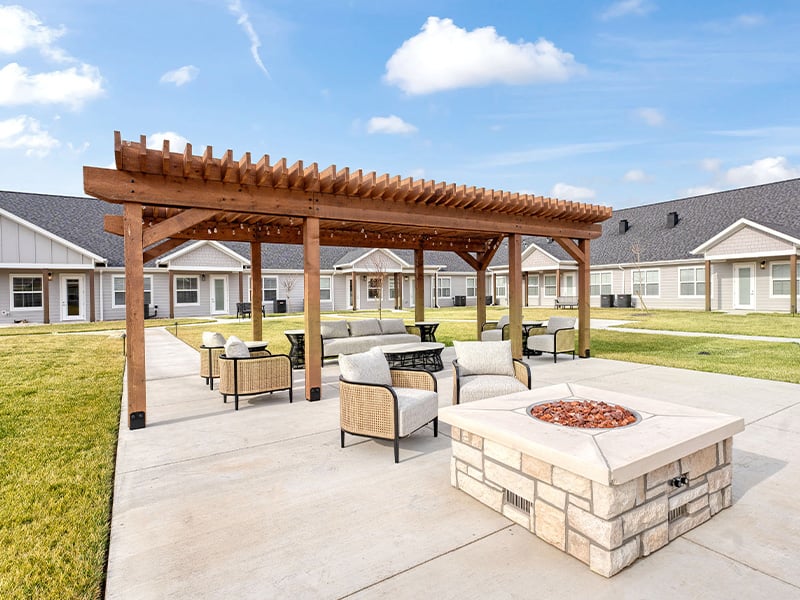 An inviting outdoor patio space with a wooden pergola with fireplace at Cedarhurst of Salina senior living community