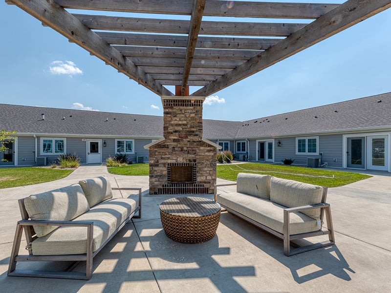 An inviting outdoor patio space with a wooden pergola with fireplace at Cedarhurst of Springfield, IL senior living community