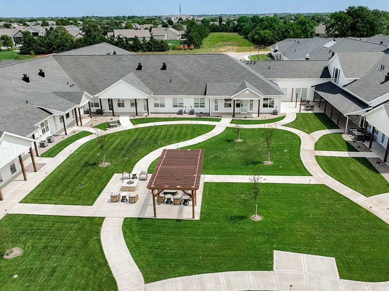 Aerial view of outdoor green space at Cedarhurst of Wichita  with paved walking paths and a covered pergola