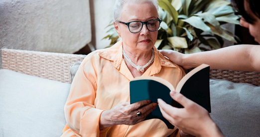 Dementia care resident reading book with caregiver 