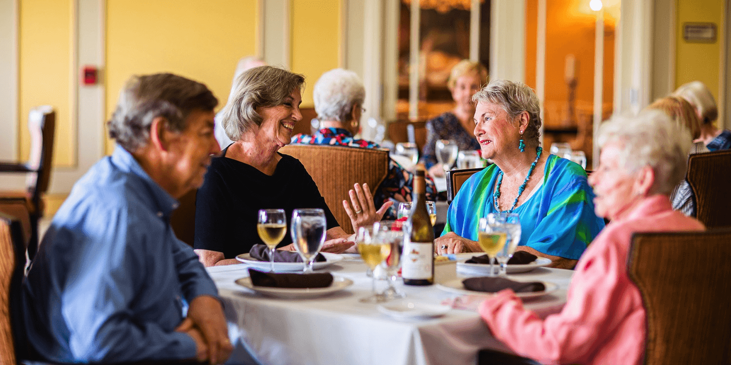 Residents drinking wine together at a dining room table