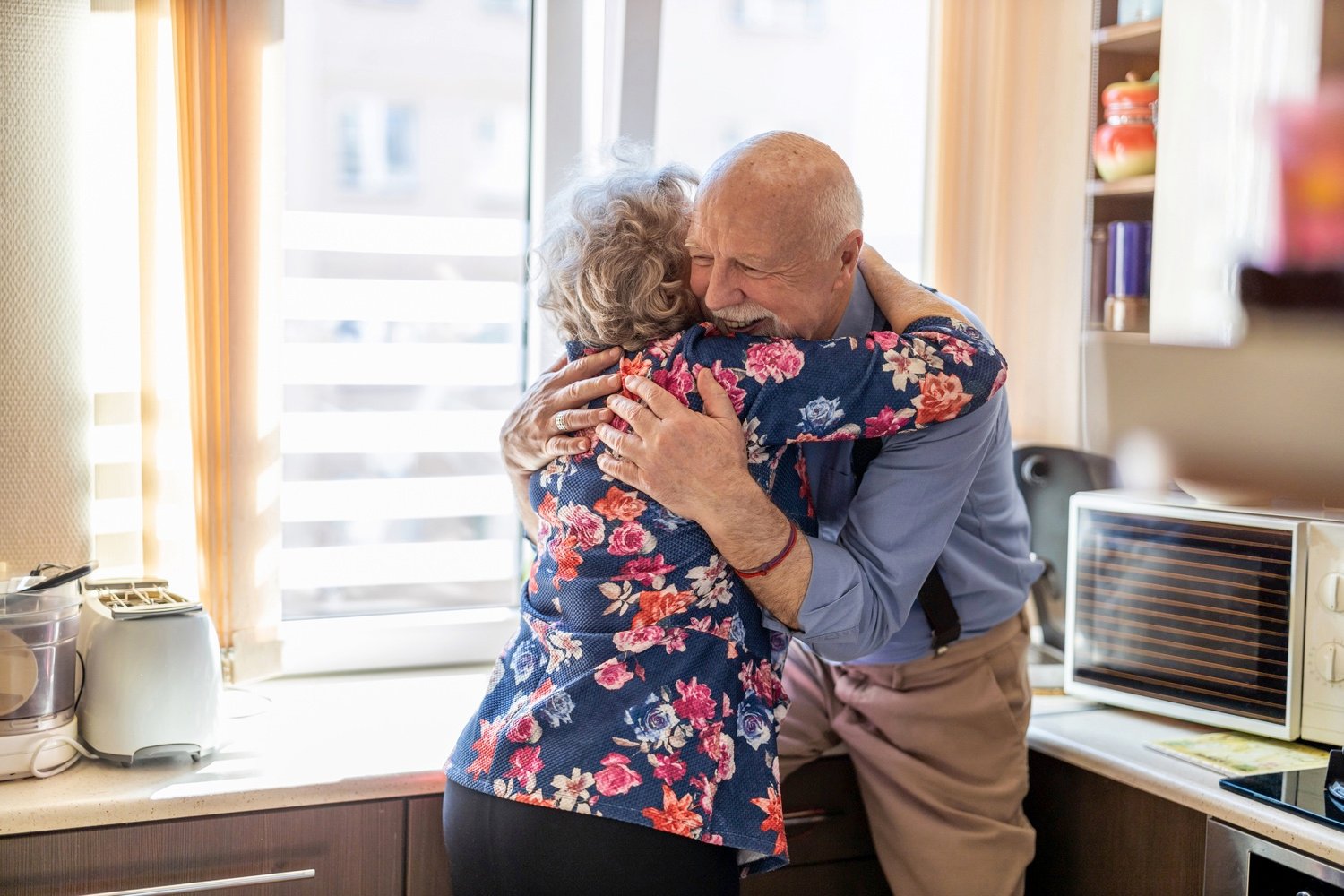 Elderly couple embracing and smiling in the kitchen