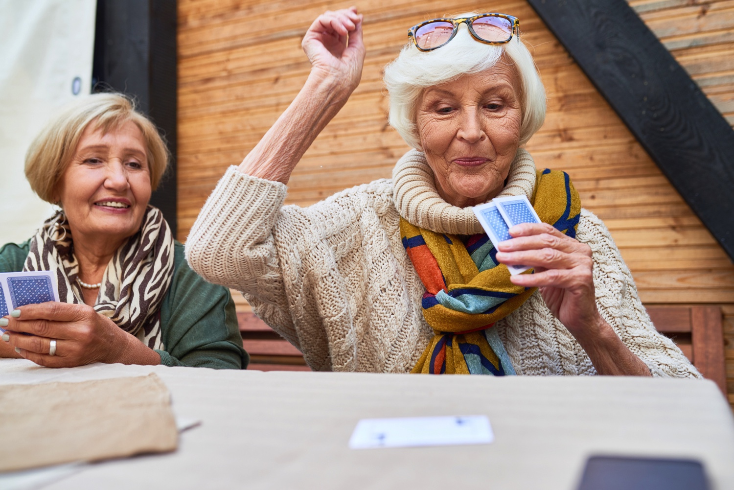 Two senior women playing a card game while seated at a table