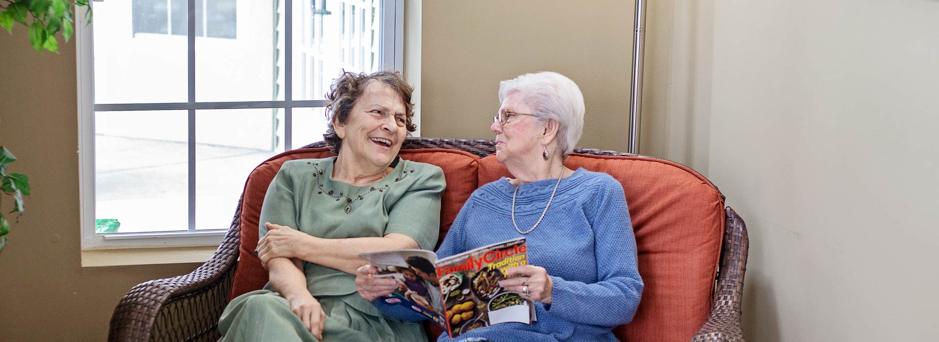 Two memory care patients socializing over a magazine