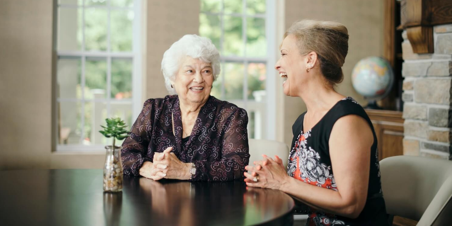 smiling senior woman having conversation with laughing woman